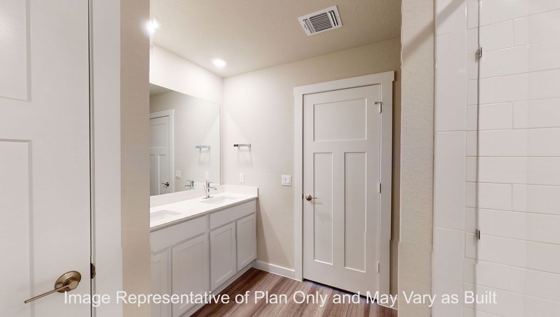 Harris primary bathroom with white cabinets and countertops and vinyl plank flooring.