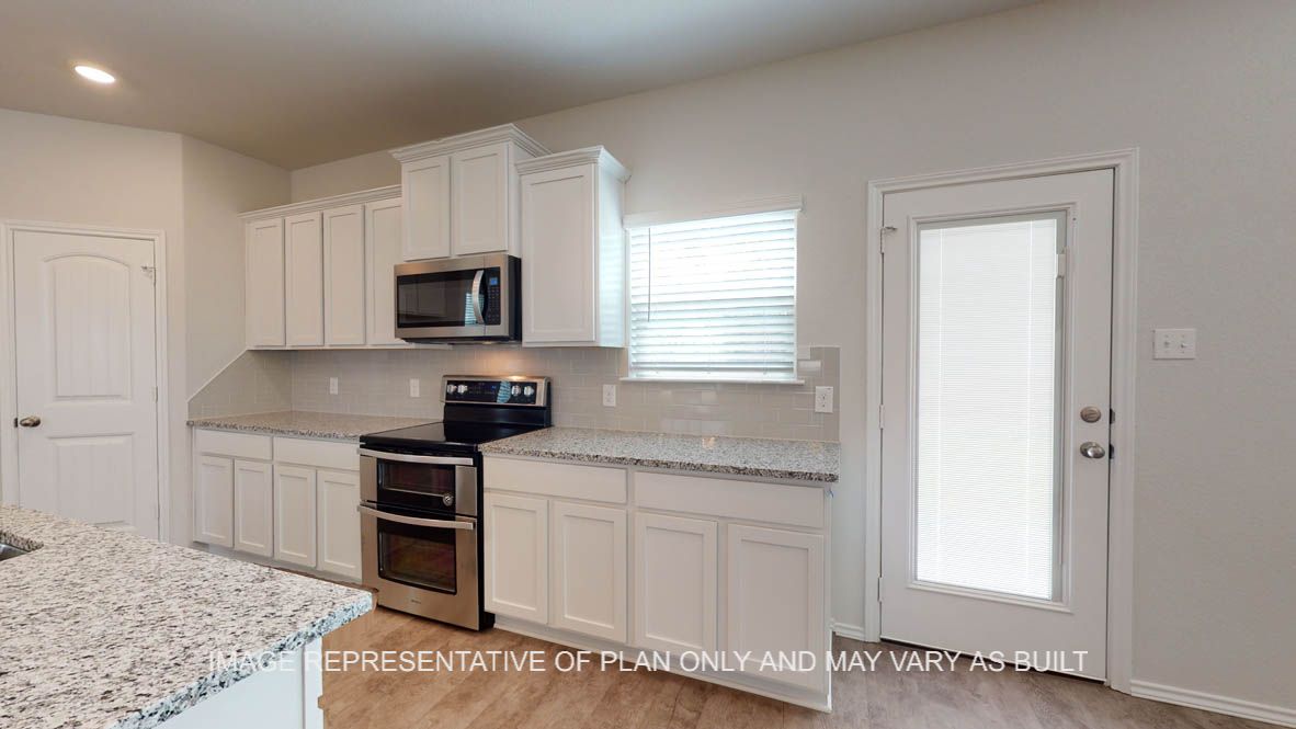 Aspen kitchen with stainless appliances and view to patio door.