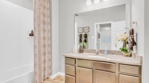 Village at Nolan Heights model home secondary bathroom with single vanity sink and mirror.