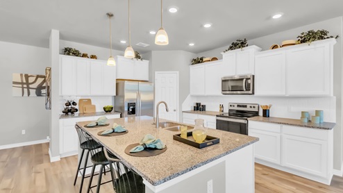 Village at Nolan Heights model home kitchen with white cabinets and granite countertops.