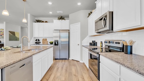 Village at Nolan Heights model home kitchen with white cabinets and granite countertops.