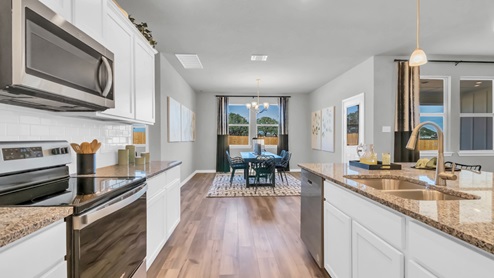 Village at Nolan Heights model home kitchen with white cabinets and granite countertops.