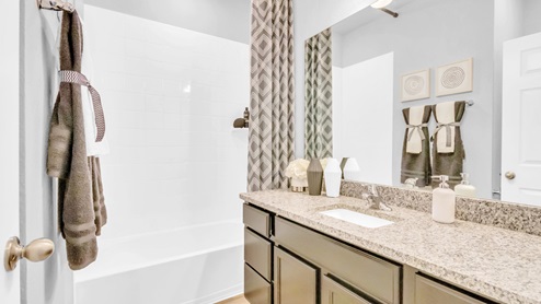 Village at Nolan Heights model home secondary bath room with single vanity and mirror.