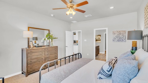 Village at Nolan Heights model home primary bedroom with a king bed and view of the primary bathroom.