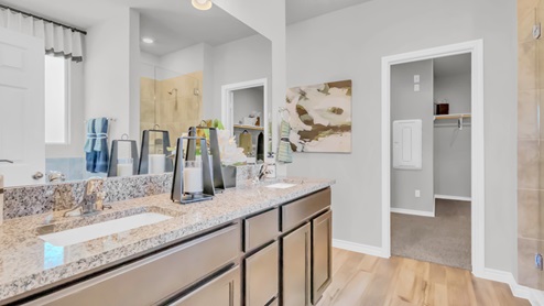 Village at Nolan Heights model home primary bathroom with double vanity sinks and view of the walk-in closet.