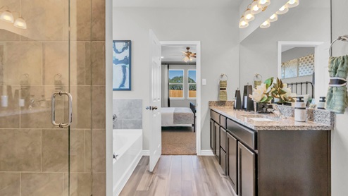 Village at Nolan Heights model home primary bathroom with walk-in shower and soaking bathtub.