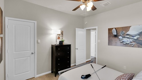 Sterling Meadows model home secondary bedroom with a full-size bed and view of the closet.