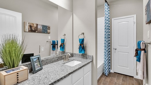 Sterling Meadows model home secondary bathroom with single vanity sink and mirror.