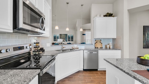 Sterling Meadows model home kitchen with white cabinets and granite countertops.