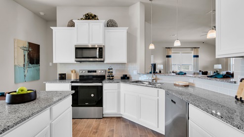 Sterling Meadows model home kitchen with white cabinets and granite countertops.