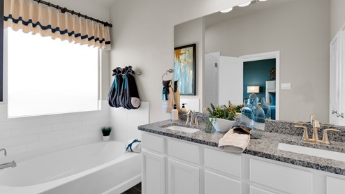 Sterling Meadows model home primary bathroom with double vanity sinks and soaking bathtub.
