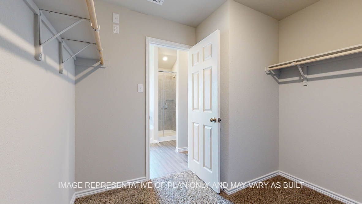 Elmwood primary bedroom walk-in closet with carpet flooring.