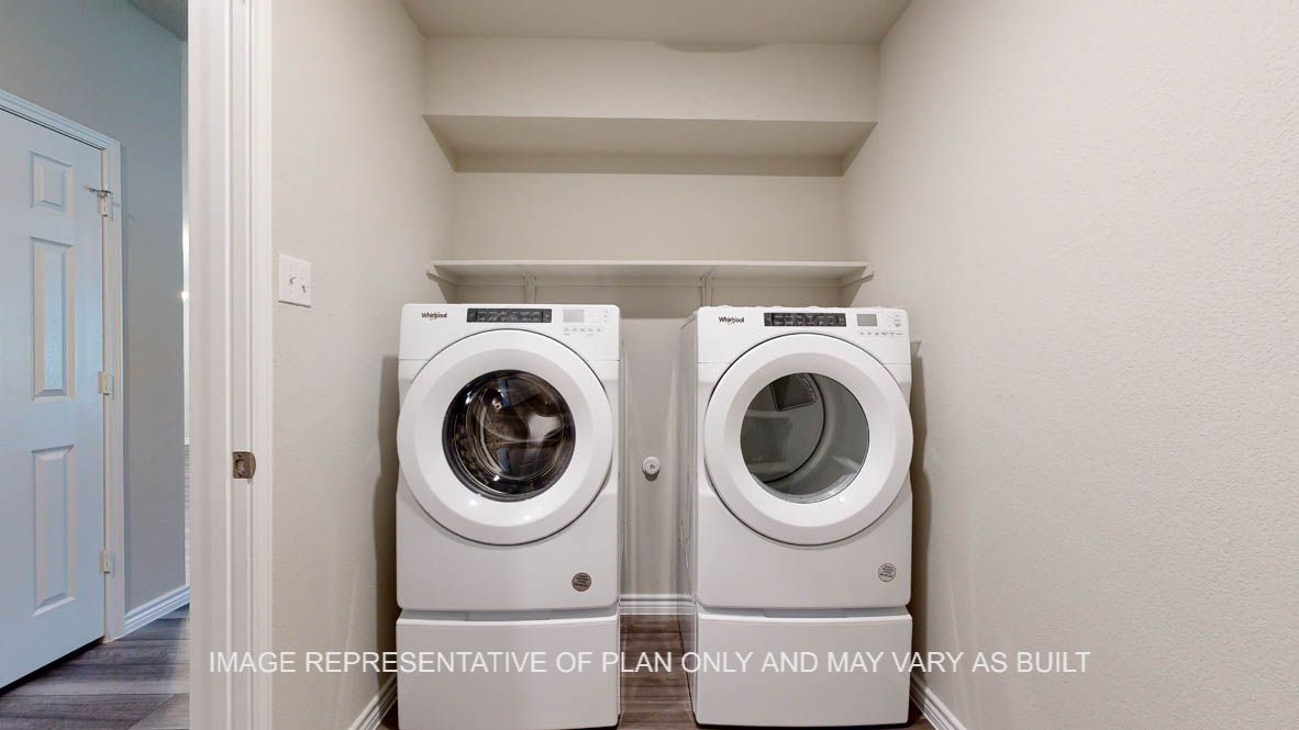 Elmwood utility room with washer and dryer and storage shelf.