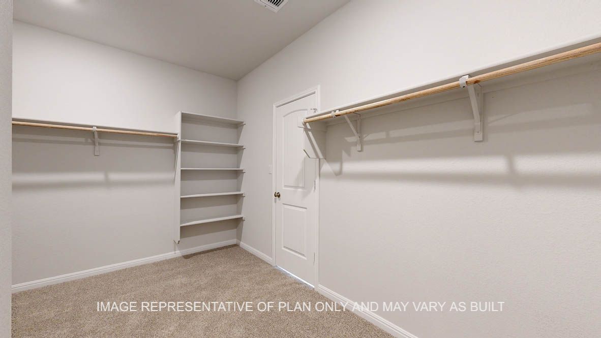 Parker primary bedroom walk-in closet with carpet flooring and storage shelves.