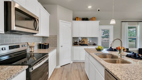 Delaware Springs model home kitchen white cabinets and granite countertops.