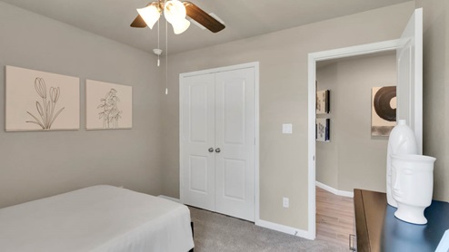 Delaware Springs model home secondary bedroom with a twin bed and view of the closet.