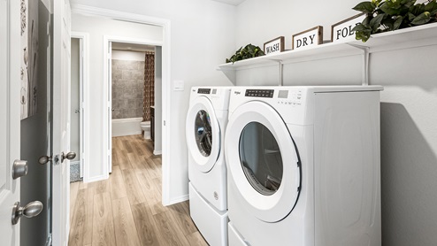 Mitchell Farm model home utility room with washer and dryer and storage shelving.