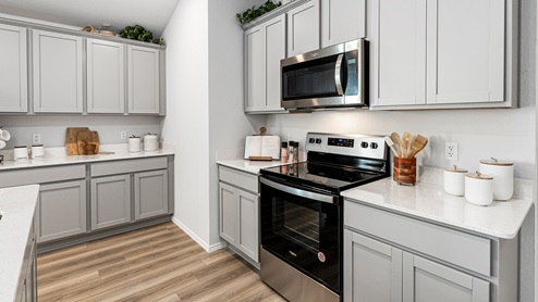 Mitchell Farm model home kitchen with gray cabinets and quartz countertops.
