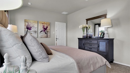 Reynolds Crossing model home primary bedroom furnished with king-sized bed.
