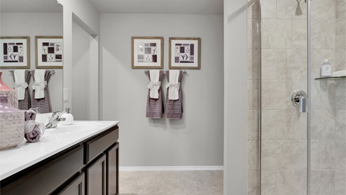 Reynolds Crossing model home primary bathroom with white cultured marble countertops and dark cabinets.