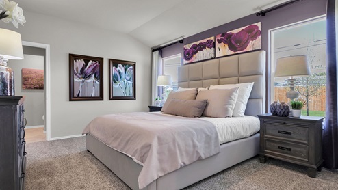 Reynolds Crossing model home primary bedroom furnished with king-sized bed.