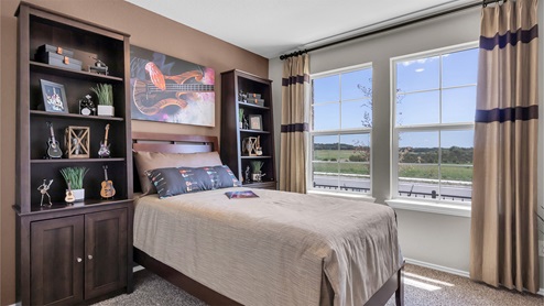 Reynolds Crossing model home secondary bedroom furnished.