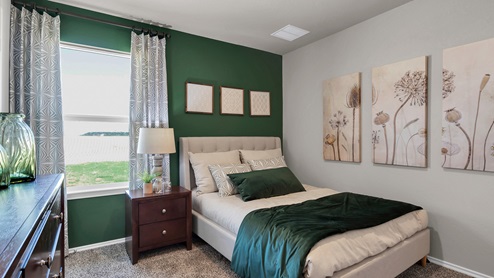 Victory Ranch secondary bedroom with green accent wall and bedroom furniture.