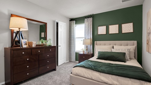 Victory Ranch secondary bedroom with green accent wall and bedroom furniture.