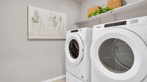 Victory Ranch model home utility room with front load washer and dryer.