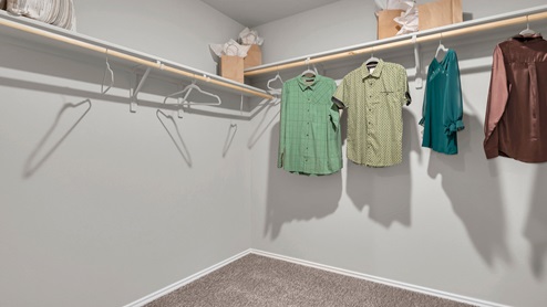 Victory Ranch primary bedroom walk-in closet with carpet flooring.