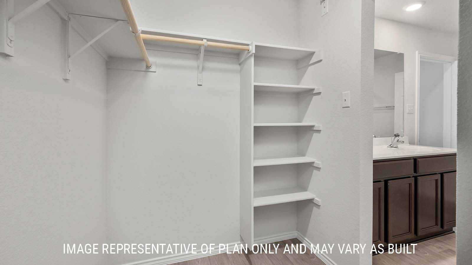 Ashburn primary closet with shelving for storage and view of primary bathroom.