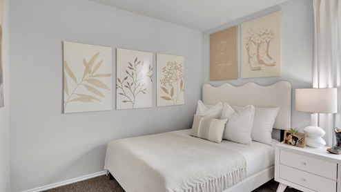 West Canyon Trails Model Home Secondary bedroom decorated with furniture, carpet flooring and light painted walls.