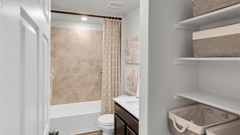Eastern Wells Model Home secondary bathroom with dark cabinets and white countertops.