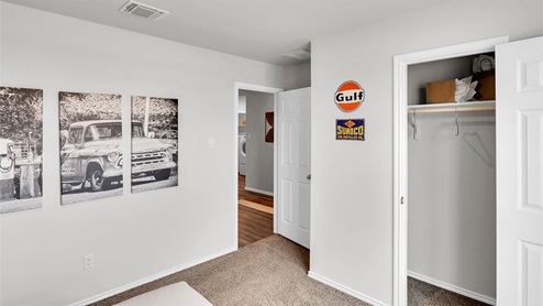Eastern Wells Model Home secondary bedroom with closet door and wall decor.