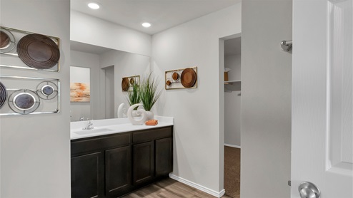 Eastern Wells Model Home primary bathroom with dark cabinets and white countertops.