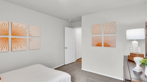 Eastern Wells Model Home secondary room with orange wall art accents and twin bed.