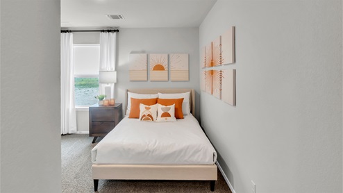 Eastern Wells Model Home secondary bedroom with bed and wall decor.