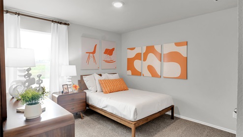 Eastern Wells Model Home secondary bedroom furnished with bed and wall decor.