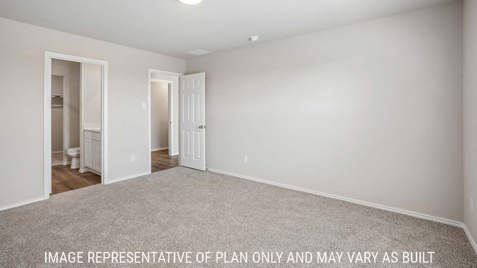 Cooper primary bedroom with carpeted flooring and view of primary bathroom.