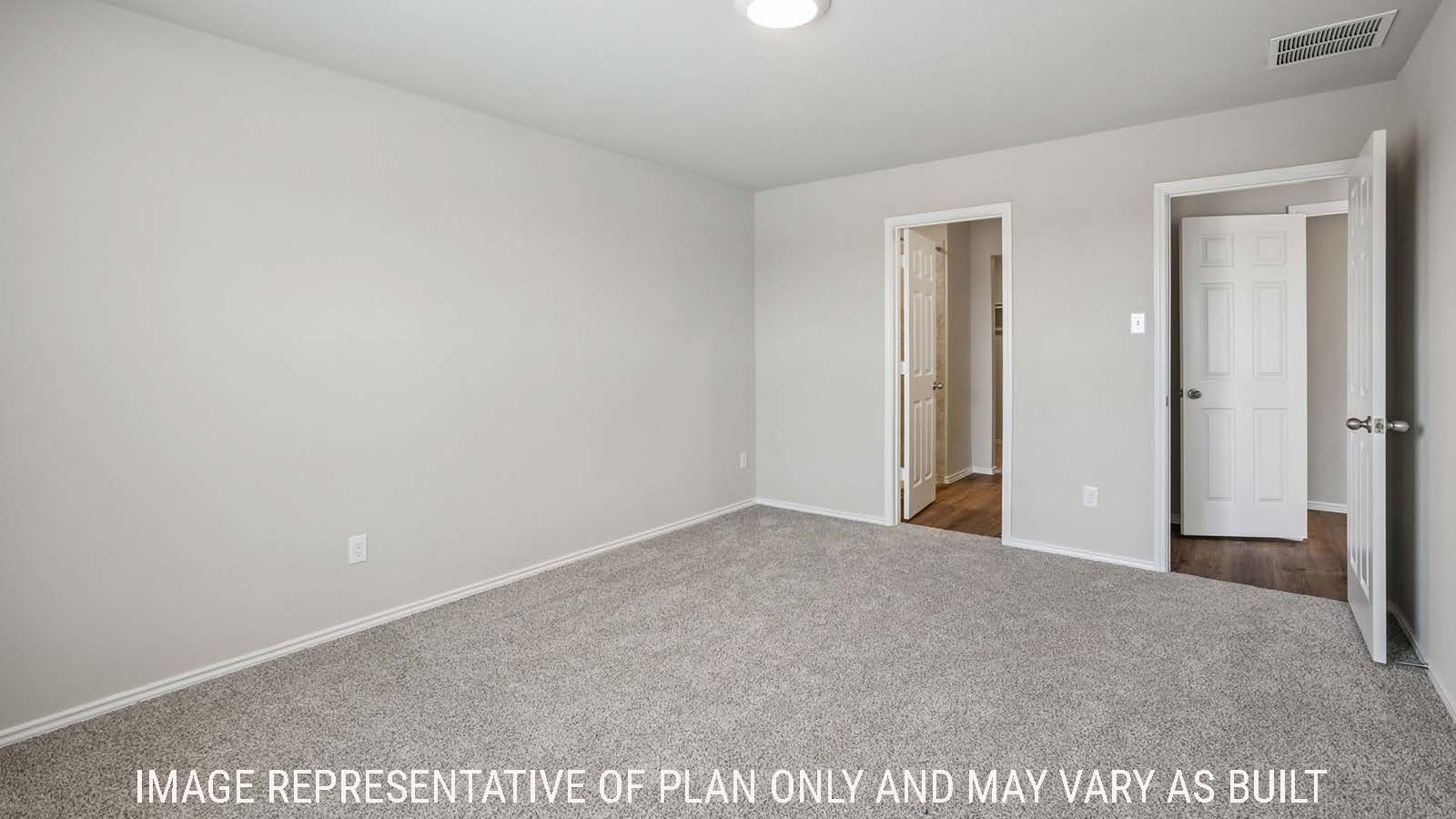 Cooper primary bedroom with carpeted flooring and view of primary bathroom.