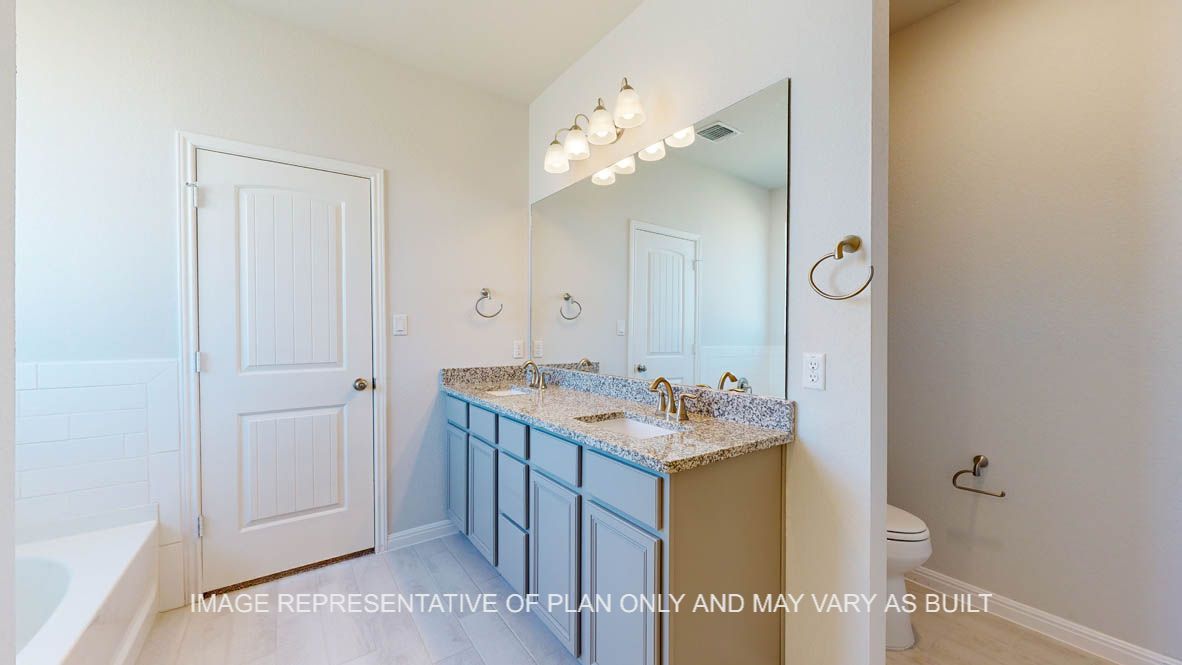 Parker primary bath with light griege cabinets and granite countertops and dual vanities.
