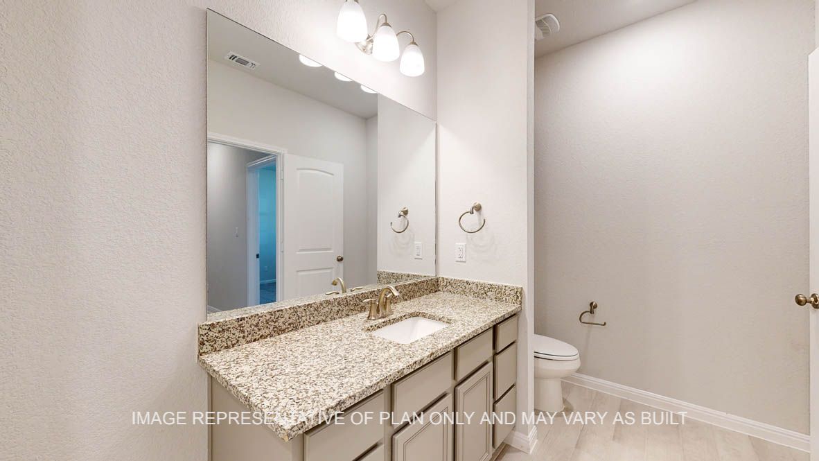 Parker secondary bath with granite countertops and wood look tile flooring.