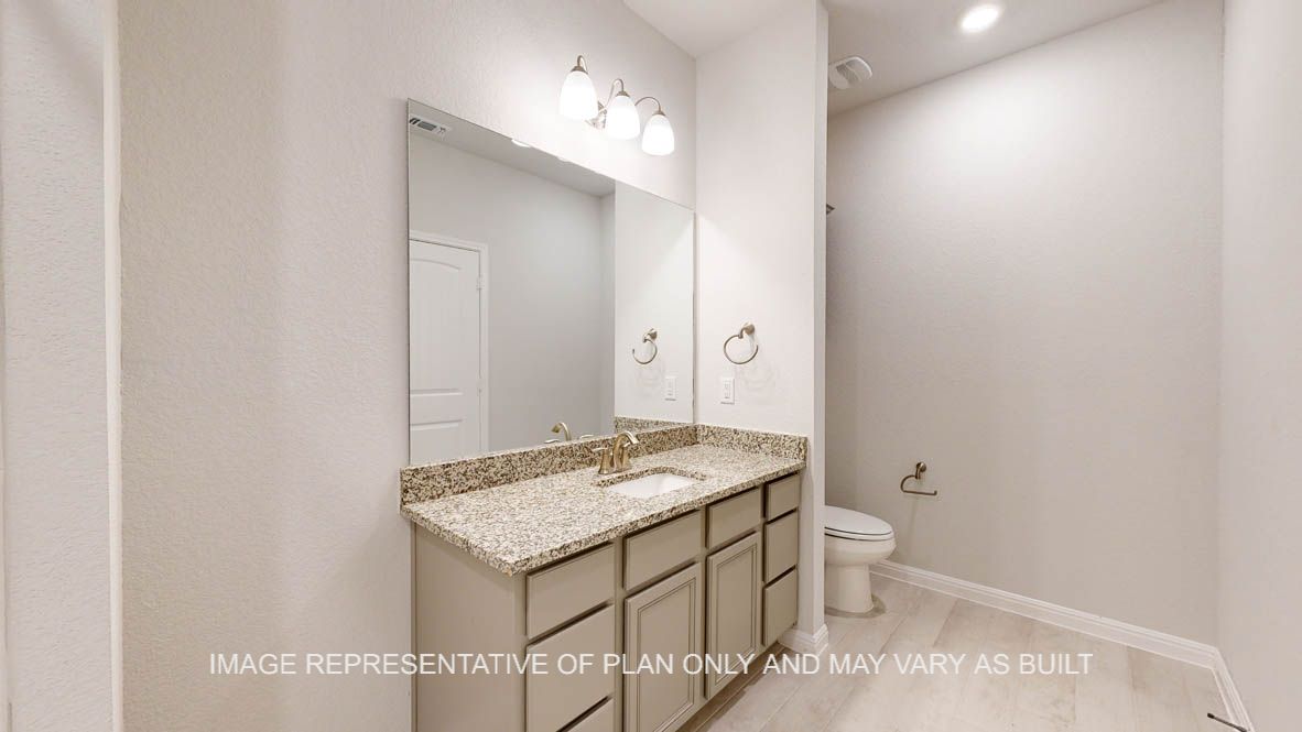 Parker secondary bath with granite countertops and wood look tile flooring.