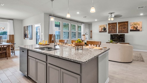 Country Meadows model home kitchen with granite tops and gray cabinets.