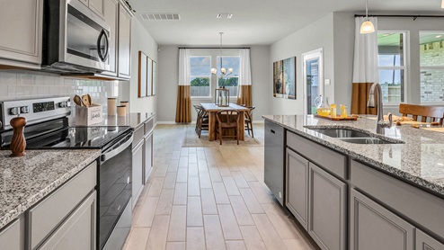 Country Meadows model home kitchen with granite tops and gray cabinets.