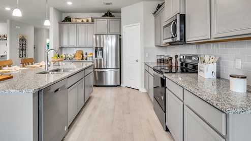 Country Meadows model home kitchen with granite tops and gray cabinets.