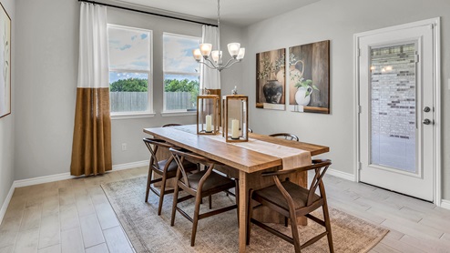 Country Meadows model home dining room with wood look tile and staged with furniture.