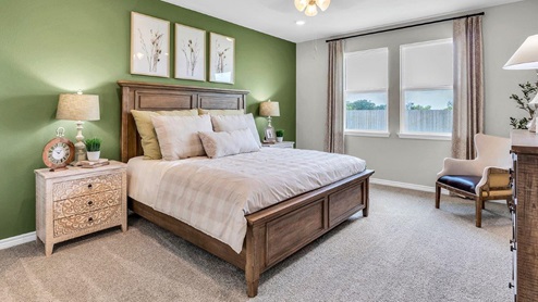 Country Meadows primary bedroom with view of windows and staged with king sized bed.