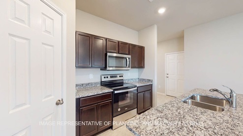 Elgin kitchen with dark cabinets, granite and tile flooring.
