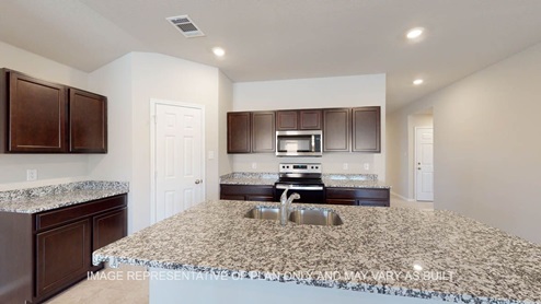 Texas Cali kitchen with dark cabinets, granite and tile flooring.